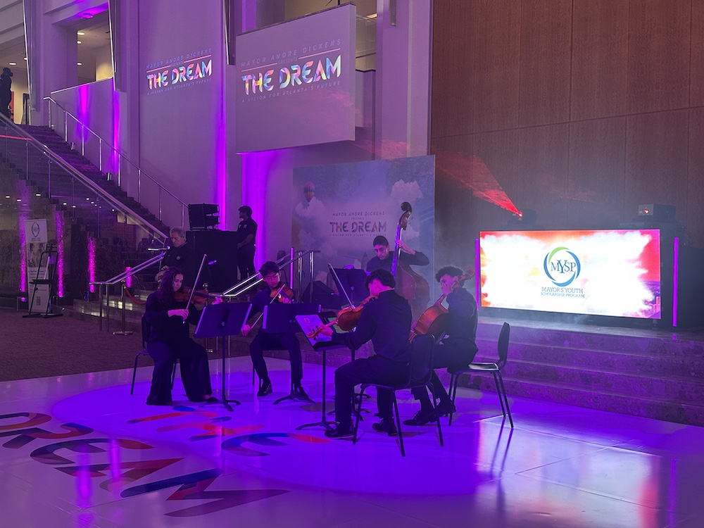 five string musicians performing in an event space with ambient lighting