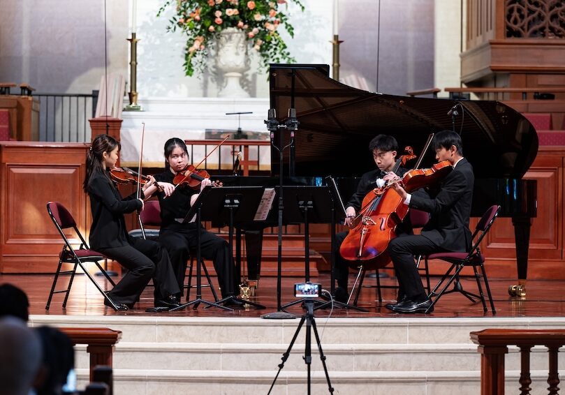 four string musicians performing on stage